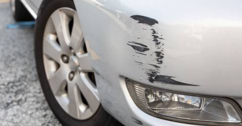 Een grijze auto met wat lichte schade op de voorbumper