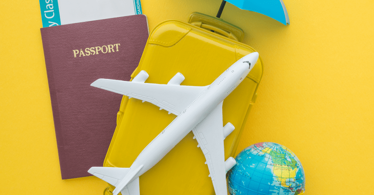 Campagne vakantiegevoel; afbeelidng van paspoort, vliegtuig, wereldbol, koffer en verzekeringsparaplu op een gele achtergrond